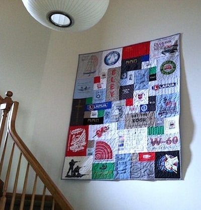 T-shirt quilt hanging in stairway made by Too Cool T-shirt Quilts