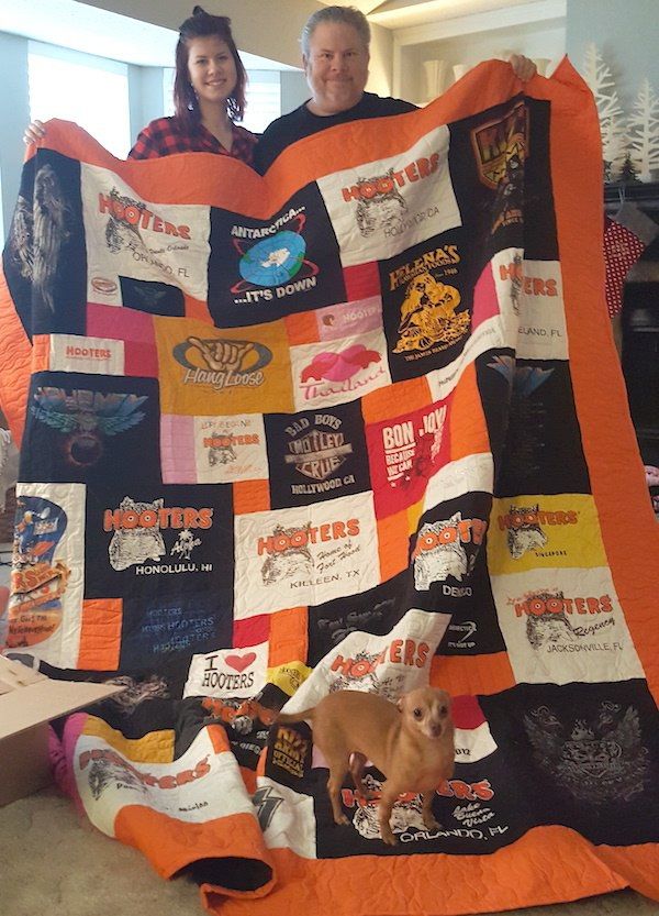 A daughter and father holding her T-shirt quilt at Christmas time. 