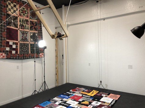 A shot of the photo studio at Too Cool T-shirt quilts in operation. This shows the black stage and the camera in mid-lift to the ceiling. 