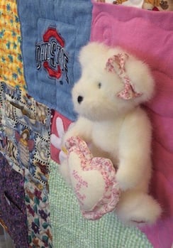 Stuffed bear on a memory quilt by Too Cool T-shirt Quilts