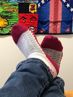 Socks on my feet in front of a bicycle jersey quilt