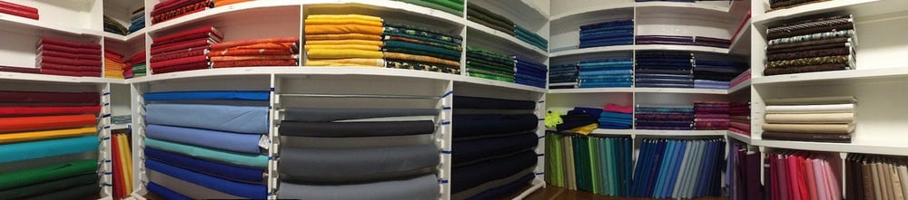 This is a panoramic photo of the fabric room at Too Cool T-shirt Quilts. It shows some of the backing color choices available. 
