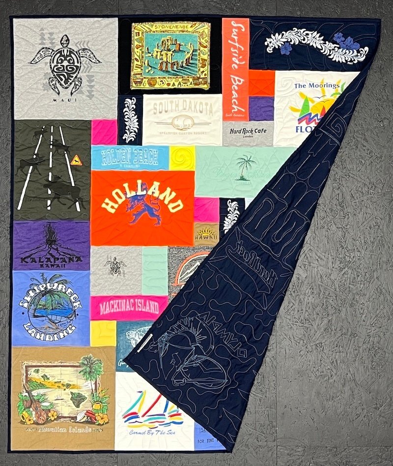 A Too Col T-shirt quilt showing the back side folded over onto the front side. You see the quilting on the back