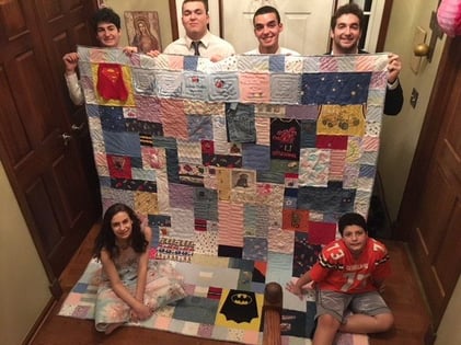 A family enjoying a baby clothes quilt made from all 6 kids' clothing