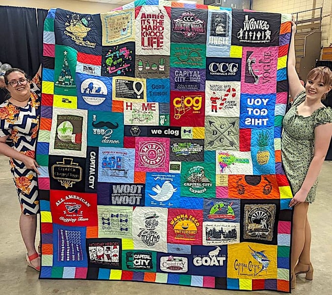 two people holding graduation quilt in a gym by Too Cool T-shirt Quilts